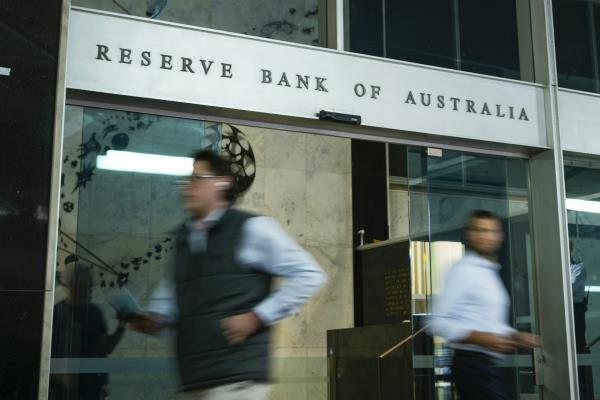 A sign reading reserve bank of australia with people rushing past